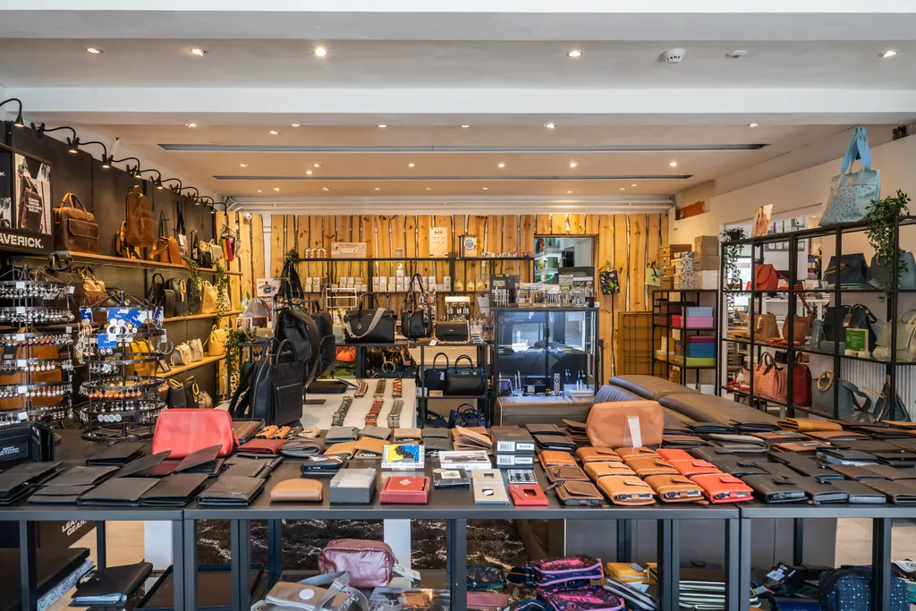 De lederwarenafdeling van Maves met handtassen, rugzakken en portefeuilles tegen een houten wand